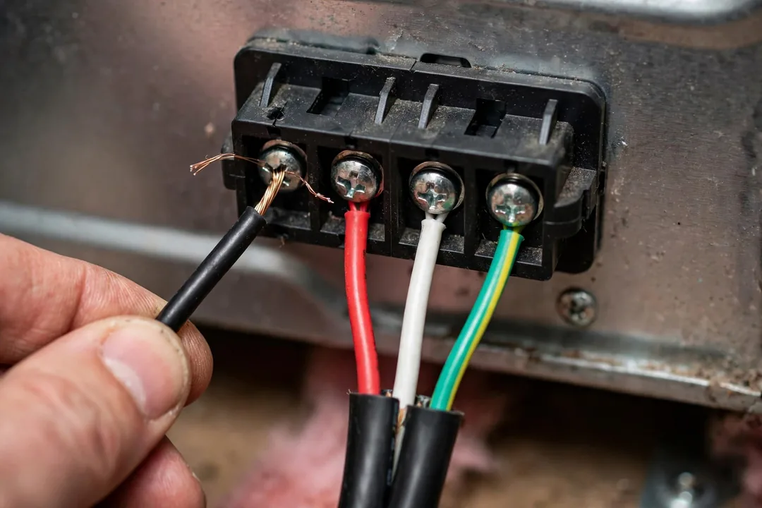 3 Wire 4 Wire Dryer Cord: technician wiring a dryer cord to the terminal block on the back of a dryer